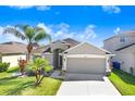 Single-story home boasts a neat lawn, mature palm trees, and a convenient two-car garage at 15414 Fire Rock Pl, Ruskin, FL 33573
