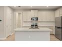 Modern kitchen featuring white cabinets, stainless steel appliances, a center island, and wood-look flooring at 20411 Symphony Pl, Venice, FL 34293
