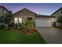 Charming single-story home with a stone facade, well-manicured landscaping, and a brick driveway at 21577 Violet Periwinkle Dr, Land O Lakes, FL 34637