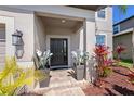 Covered front entry featuring updated landscaping, potted plants, and a secure doorway at 4923 Eagle Rock Dr, Wimauma, FL 33598