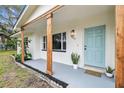 Inviting front porch with a welcoming blue door, wooden support beams, and stylish plants that enhance the home's curb appeal at 7310 Donna Dr, New Port Richey, FL 34652