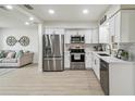 Open-concept kitchen featuring stainless steel appliances, white cabinets, and seamless flow into the adjacent living area at 7310 Donna Dr, New Port Richey, FL 34652