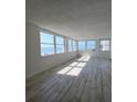 Bright, empty living room featuring wood floors and large windows with an ocean view at 17408 Gulf Blvd # 201, Redington Shores, FL 33708