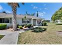 Charming single-story home with well-maintained landscaping featuring mature trees, shrubs, and a walkway leading to the front door at 1902 Dandridge St # 6, Sun City Center, FL 33573