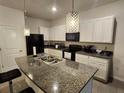 Modern kitchen featuring granite countertops, white cabinetry, stainless steel appliances and pendant lighting at 3267 Pleasant Willow Ct, Brandon, FL 33511