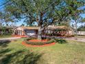 Traditional brick home with a beautifully landscaped front yard and a circular flower bed around a mature tree at 6804 Sea Gull S Dr, St Petersburg, FL 33707