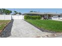 Long paved driveway leading to a well-maintained home with a white fence and lush green lawn at 715 44Th Ne Ave, St Petersburg, FL 33703