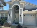 Up close view of the home's entryway and garage, featuring manicured landscaping and a security system at 1210 Paradise Lake Dr, Tarpon Springs, FL 34689