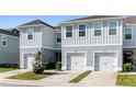 Charming two-story townhome featuring a gray exterior, a well-manicured lawn, and individual car garages at 12309 Grizzly Ln, New Port Richey, FL 34654