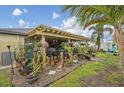 Relaxing backyard featuring a covered patio, lush greenery, various potted plants, and a private garden area at 14407 Alistar Manor Dr, Wimauma, FL 33598