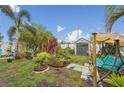 Lush backyard oasis with various plants, trees, shed, decorative elements, bench, and a cozy swing seat at 14407 Alistar Manor Dr, Wimauma, FL 33598