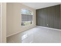Modern, minimalist bedroom showcasing a decorative wall, large window, and neutral tile flooring at 18413 Eastwyck Dr, Tampa, FL 33647
