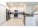 Modern kitchen with stainless steel appliances, granite counters, white cabinets, and tile floors at 21385 Darter Rd, Land O Lakes, FL 34638