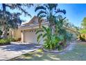Home exterior with a two-car garage, driveway, and tropical landscaping at 2542 Clareside Dr, Valrico, FL 33596