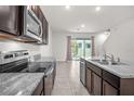 An open kitchen with stainless steel appliances, dark cabinets, and granite countertops overlooking the living area at 2892 Beluga Bay Dr, Odessa, FL 33556
