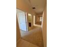 Hallway with neutral carpet and paint, leading to bedrooms and a bathroom with wood cabinets at 3616 Beaumont Loop, Spring Hill, FL 34609