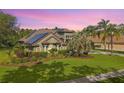 Beautiful home with a well-maintained lawn, lush landscaping, and a solar panel roof at 5384 Mira Vista Dr, Palm Harbor, FL 34685
