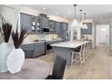 Inviting kitchen featuring gray cabinets, stainless steel appliances, an island with seating, and hardwood flooring at 18264 Chromata Dr, Venice, FL 34293