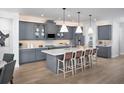 Beautiful kitchen with gray cabinets, white countertops, stainless appliances, island with bar seating, and hardwood floors at 18264 Chromata Dr, Venice, FL 34293