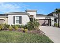 Single-story home with a landscaped front yard, two-car garage, and black window shutters at 33410 Castaway Loop, Wesley Chapel, FL 33543