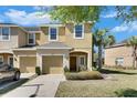 Charming townhome with a well-manicured lawn, a one-car garage, and tropical palm tree in a sunny neighborhood at 6907 Holly Heath Dr, Riverview, FL 33578
