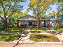 Inviting craftsman-style house with a brick-columned porch, mature trees, and lush green landscaping at 803 S Packwood Ave, Tampa, FL 33606