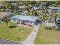 Charming single-story home featuring a metal roof, a well-manicured lawn, and tropical landscaping at 1740 Grove Dr, Clearwater, FL 33759