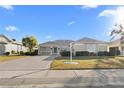 Tan one-story home with landscaped front yard and driveway with a white decorative lamp post at 2325 W Del Webb Blvd, Sun City Center, FL 33573