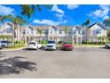 Townhouse complex with multiple parking spaces, set against a backdrop of blue skies and lush trees at 435 Kensington Lake Crk, Brandon, FL 33511
