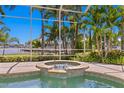 Relaxing spa beside the screened pool area with tropical landscaping and clear blue skies at 708 Islebay Dr, Apollo Beach, FL 33572