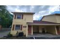 Exterior of a condo with yellow stucco, brown trim and carport with cracked pavement at 7502 Bolanos Ct, Tampa, FL 33615