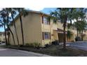 Exterior of the condo with yellow walls, brown trim, and some palm trees and patchy grass at 7502 Bolanos Ct, Tampa, FL 33615