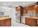 A kitchen featuring updated appliances, wood cabinets, granite countertops, and white tile floors at 7512 Dolonita Dr # 7512, Tampa, FL 33615