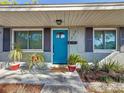 A brightly painted blue front door is framed by fresh landscaping, contrasting shutters, and light-colored siding at 777 62Nd N Ave, St Petersburg, FL 33702