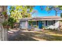 Charming single-story home with a well-manicured lawn, vibrant blue door, and an attached garage at 777 62Nd N Ave, St Petersburg, FL 33702