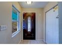 Interior foyer featuring a dark wooden front door with decorative glass and tile flooring at 8740 Forest Lake Dr, Port Richey, FL 34668