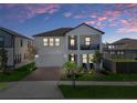 Charming two-story home featuring a balcony and a well-manicured lawn at dusk at 9817 Coneflower Ct, Land O Lakes, FL 34637