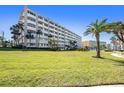Exterior shot of the condo building highlighting a well-manicured lawn and palm trees at 100 Bluff View Dr # 614A, Belleair Bluffs, FL 33770