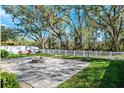 Backyard patio featuring pavers and a firepit, surrounded by a white fence and mature trees at 13001 Satin Lily Dr, Riverview, FL 33579