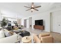 Bright, open living room with modern furnishings, ceiling fan, and a view of the kitchen area at 13001 Satin Lily Dr, Riverview, FL 33579