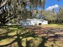 Charming one-story home with attached garage, shaded by mature oak trees at 1502 S Wiggins Rd, Plant City, FL 33566