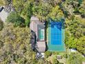 Beautiful aerial view of estate with tennis court and screened in pool surrounded by mature trees at 2112 Laurence Dr, Clearwater, FL 33764