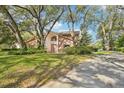 Exterior view of a beautiful home with mature trees, lush lawn, and winding driveway at 2112 Laurence Dr, Clearwater, FL 33764