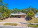 Charming home featuring a brick driveway, covered patio, and mature tropical landscaping at 2121 Park N St, St Petersburg, FL 33710