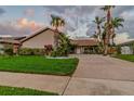 Inviting single-story home with meticulous landscaping, featuring palms and other lush greenery, with a grey sky at 6109 Schooner Way, Tampa, FL 33615