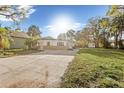 Wide front view of a one-story home with stone detailing, surrounded by trees and a spacious front yard at 7301 S Swoope St, Tampa, FL 33616