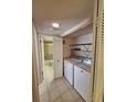 Practical laundry room with a washer, dryer, storage shelving, and a door leading to a bathroom at 1010 Bowsprit Ln # 0, Holiday, FL 34691