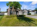 Charming home with lush green lawn, mature palm trees, three-car garage and stone accents at 11432 Leland Groves Dr, Riverview, FL 33579