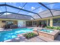 Relaxing screened in pool and spa area that includes a dining table and basketball hoop at 16318 Palmettoglen Ct, Lithia, FL 33547