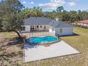 Aerial view of backyard pool with safety fence, concrete decking and white house with gray roof at 18214 Ozark Dr, Hudson, FL 34667